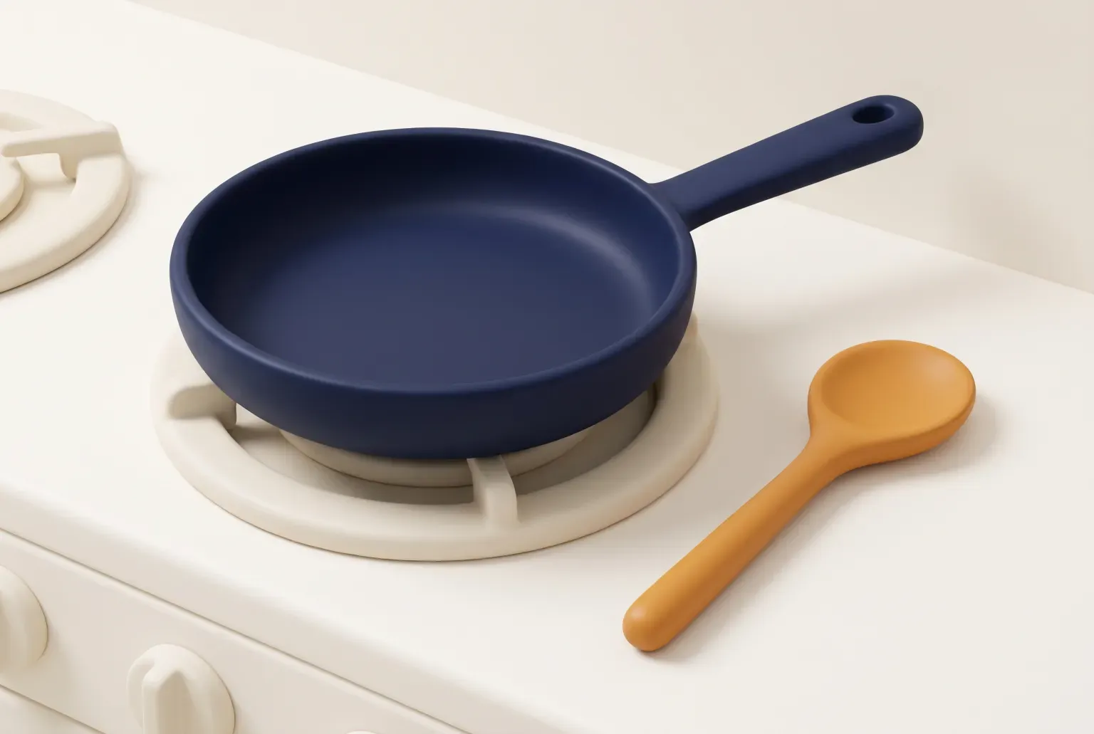 Illustration: a plain dark frying pan with a plain handle sitting on a stovetop burner beside a spoon, drawn as a soft 3D render. Not a real product.